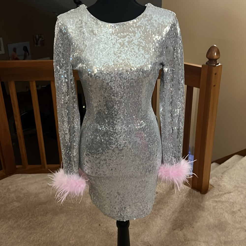 Silver long sleeved mini cocktail dress with pink feather trim on wrists.